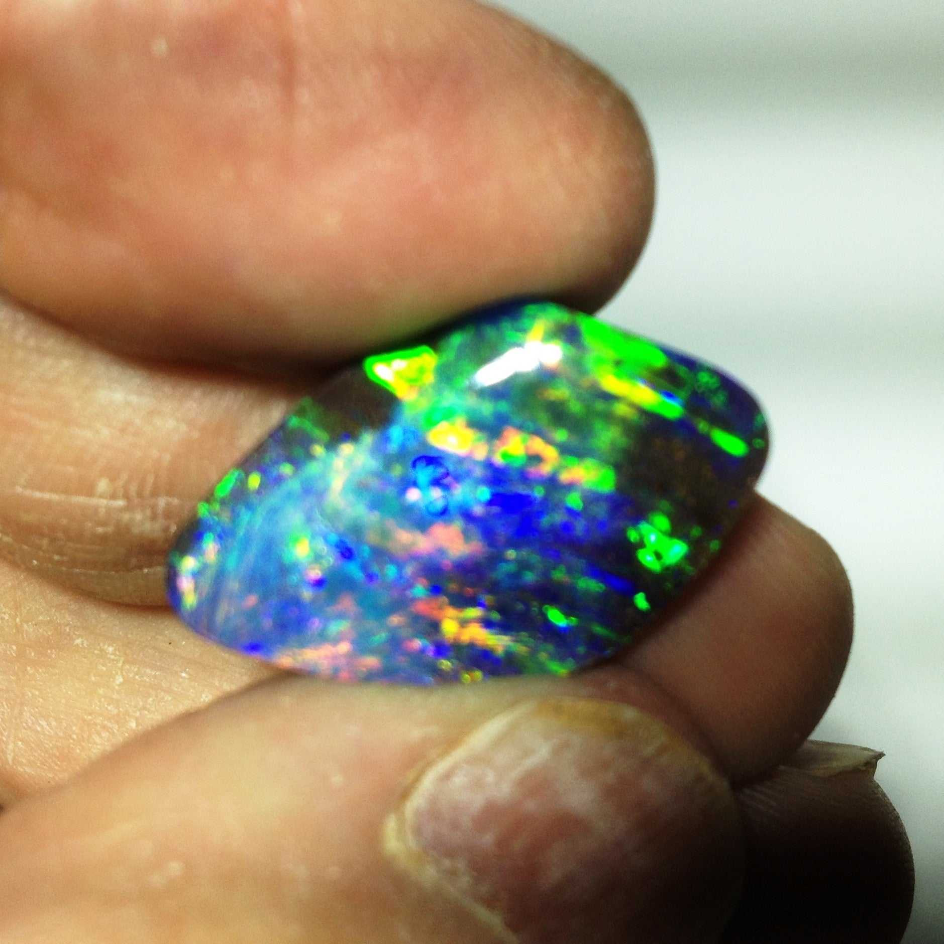 Green, orange, blue and gold solid boulder opal