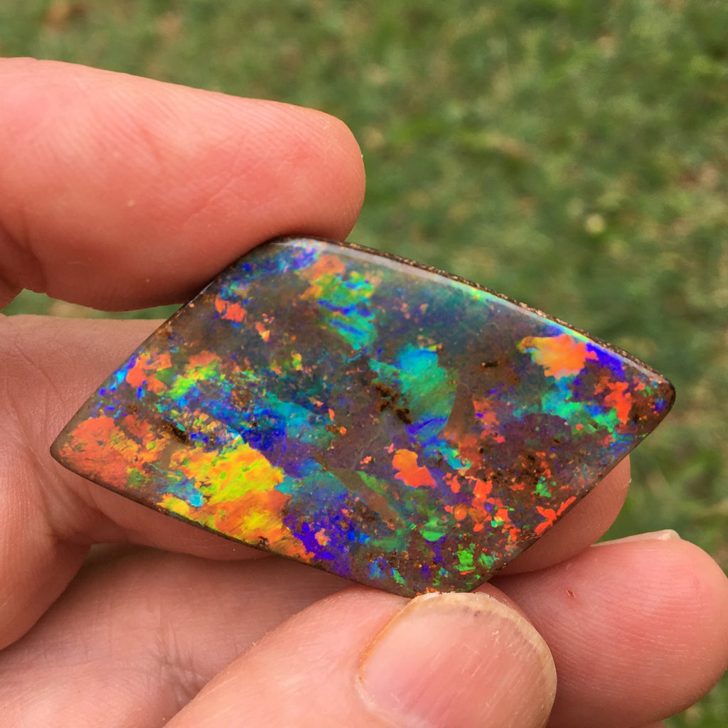 Red, orange, green, gold over violet and blue solid boulder opal